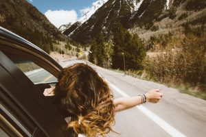 femme qui passe le bras et la tête par la fenêtre de la voiture